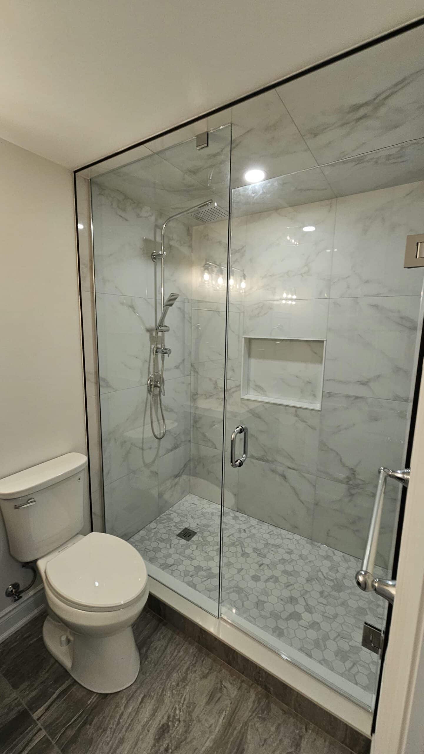 glass shower with shampoo niche and mosaic tiles on the shower floor