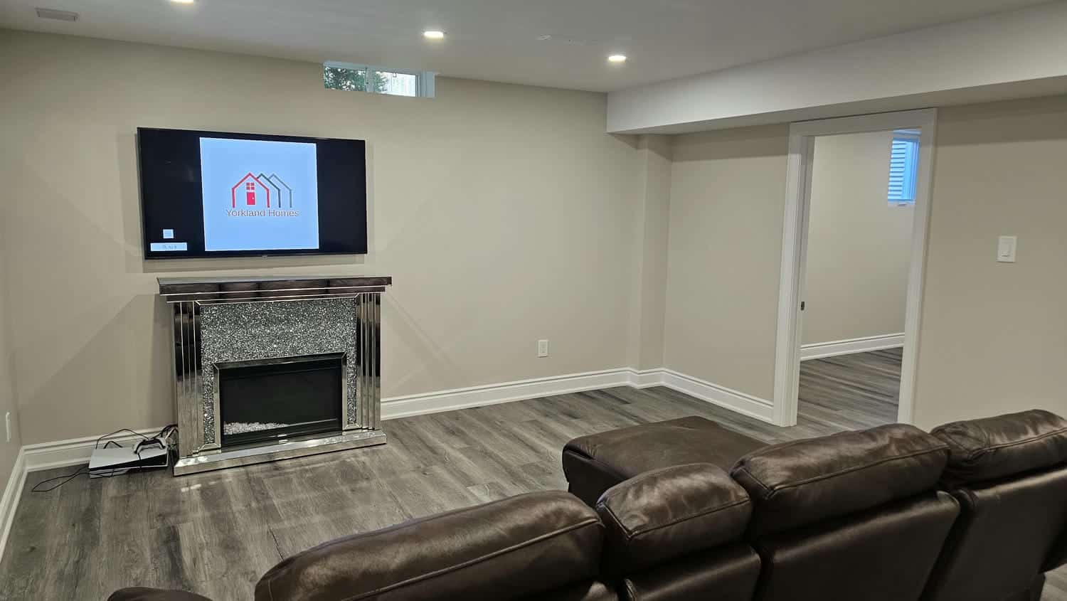 view of the basement bedroom door with couch and tv in the living room
