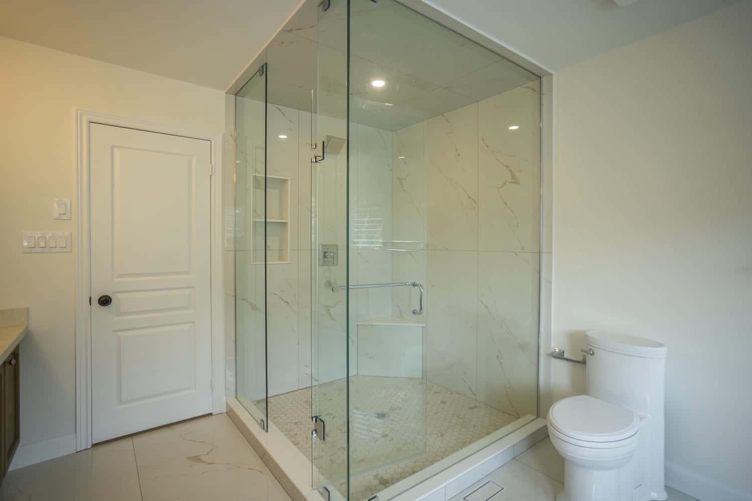 Large corner shower with a one piece toilet and Aria floor vent