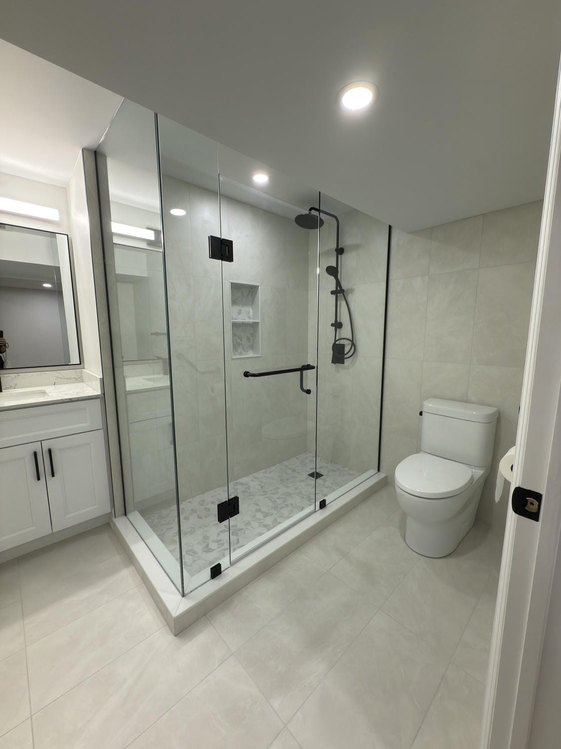 Bright 3-piece bath with a full glass shower and clean tile finish. Matte black fixtures add contrast and a sharp, modern touch.