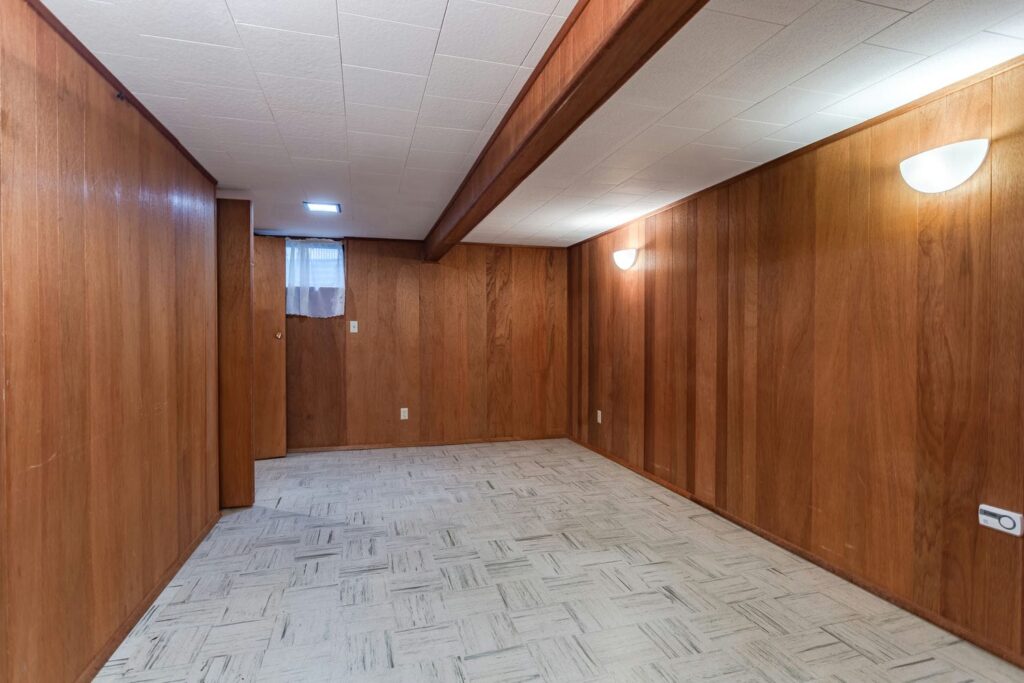 An older finished basement with a low ceiling and beam, the kind of space often assessed for underpinning