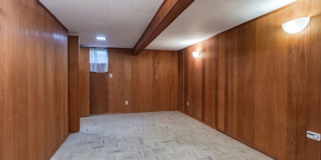 An older finished basement with a low ceiling and beam, the kind of space often assessed for underpinning